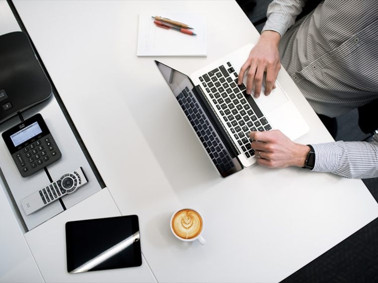 Overhead view of a desk with a laptop, tablet and notepad during a filing session